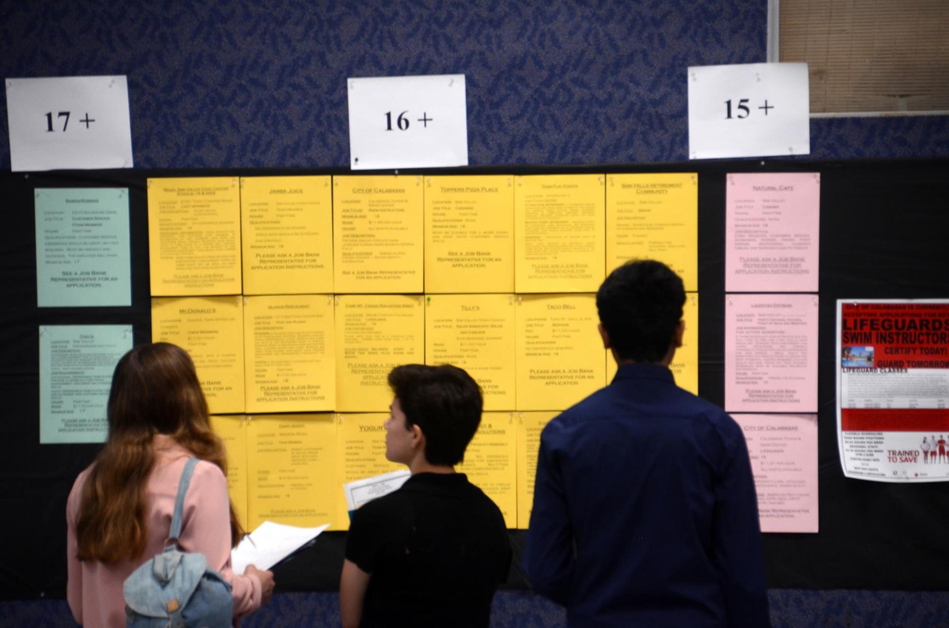 three young people browsing a job board at the YES Job and Career Expo