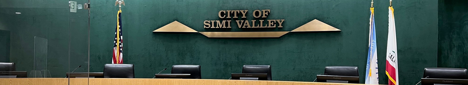 The City of Simi Valley City Council Chambers Dias flanked by U.S. Flag on the right and the City Flag and State of California Flag on the Left