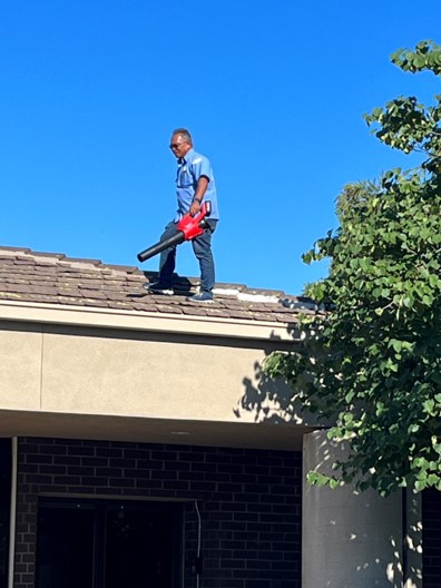 City Employee on Roof Using Leaf Blower